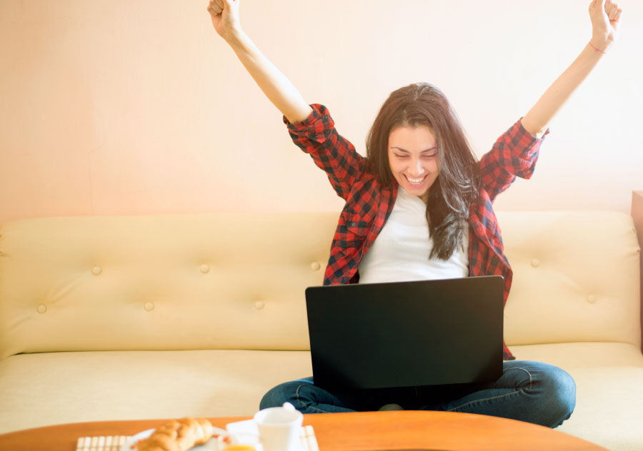 Happy woman arms raised sitting with laptop